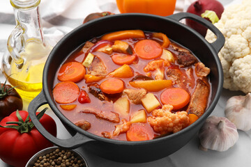Tasty homemade stew with vegetables on white tiled table, closeup