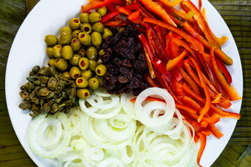 Top view of ingredients in a dish for cooking hallacas. Venezuelan traditional christmas food. Holiday season. Olive, bell pepper, onion, raisins, capers.