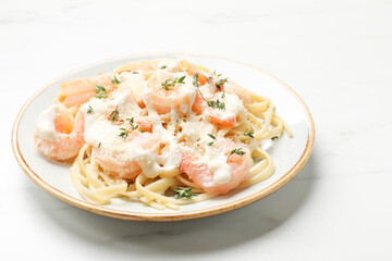 Tasty pasta with shrimps, creamy sauce and cheese on white marble table, closeup