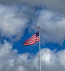 American Flag Against Blue Sky with Cumulus Clouds.