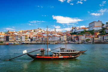 View of Porto city and Douro river with traditional boat with port wine barrels from famous tourist viewpoint Marginal de Gaia riverfront. Porto, Vila Nova de Gaia, Portugal