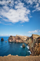 Naklejka premium Madeira Island scenic rugged landscape - Ponta do Sao Lourenco cape with descending passenger airplane, Miradouro do Abismo viewpoint. Madeira, Portugal