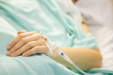 A cannula in the left wrist of a female patient lying on a bed