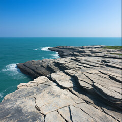 Expansive Rocky Ocean Cliff with Crashing Waves and Clear Blue Sky Creating a Stunning Coastal Landscape
