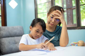 A woman is helping a young girl with her homework.