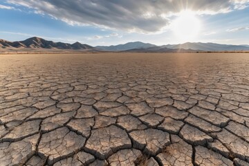 Dry cracked earth in a desert landscape and bright sun rays showcasing the texture of arid soil under the intense summer heat