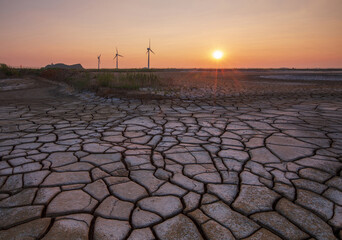 Sunset view of drought land with cracks on mud flat against wind generator turbines at Tando Port near Ansan-si, South Korea