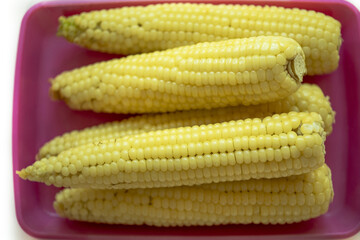 Close-up of stacked boiled corns on red plastic plate, South Korea