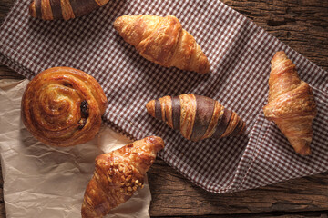 Freshly baked Raisin Danish Pastry and croissants. Arranged on a cloth and parchment paper.