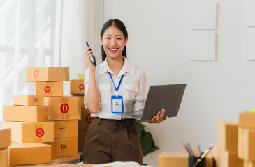 Smiling Businesswoman Running Online Business: A young Asian woman, radiating confidence, stands...