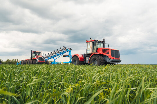 huge tractor collecting haystack in field in a nice blue sunny day