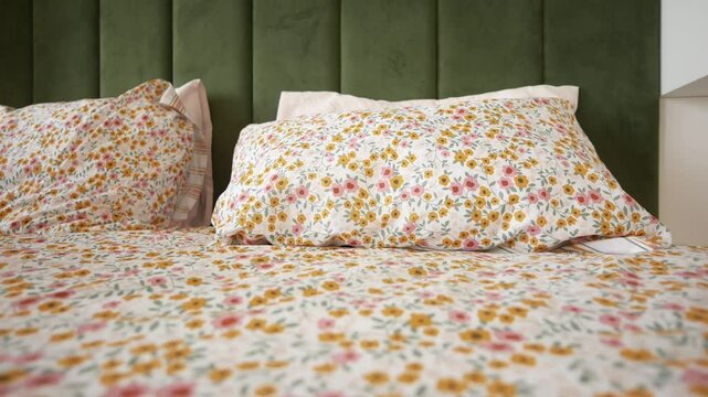 A bed with floral bedding in a bedroom with hardwood floors and cozy linens