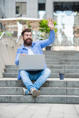 Obraz premium man freelancer has video call at coffee break. waving hello. man freelancer has video call