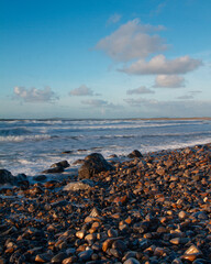 dark brown stones. sparkling ocean water. sky background