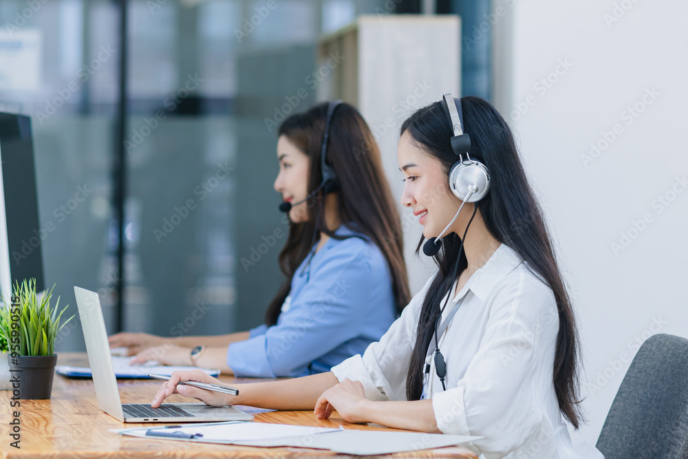 Wall mural young asian businesswoman with headset using desktop computer for customer support and online workin