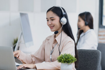 Young asian businesswoman with headset using desktop computer for customer support and online...