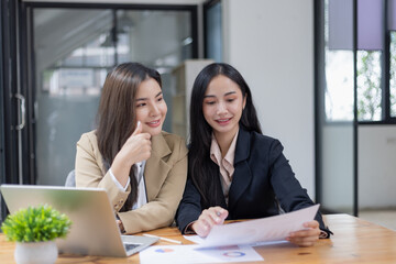 Two Asian businesswomen working on laptop computer with analyzing financial charts in the modern office, Business financial documents and planning idea project concept.