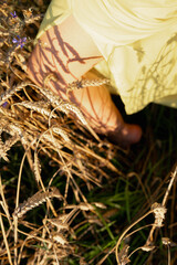 selective focus knees of female young girl in yellow dress in wheat field place for writing, fields and nature of Ukraine