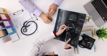 Doctor discusses results of x-ray of spine with patient in clinic, top view