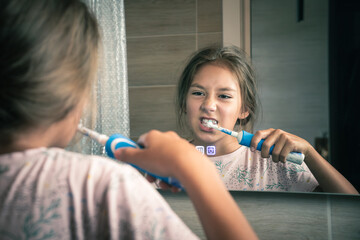 happy smiling teenage girl with toothbrush brushing teeth at bathroom. dental care, hygiene and...