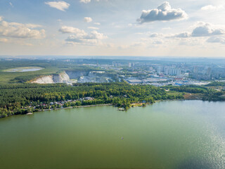 Fototapeta premium Stone quarry in the forest. Flying over the summer mixed forest during sunset. The surroundings of Yekaterinburg. Ural, Russia, Aerial View