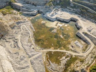 Stone quarry in the forest. Flying over the summer mixed forest during sunset. The surroundings of Yekaterinburg. Ural, Russia, Aerial View