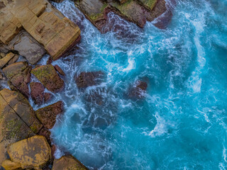 Sunrise and the blue sea washing over the rock platform