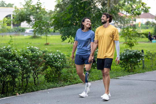 Couple with prosthetic leg from amputation walking exercise in the public park together for disability and handicap people and diversity with universal design for better accessibility infrastructure - Powered by Adobe