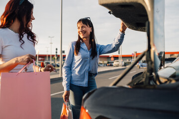 Trendy girls putting shopping bags into a trunk after shopping spree. © Zamrznuti tonovi
