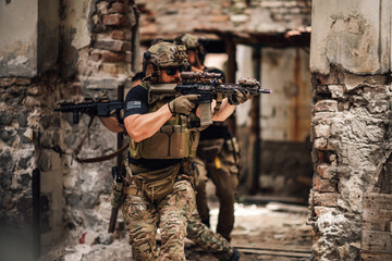 Group of army men with rifles sneaking in ruins and having mission.