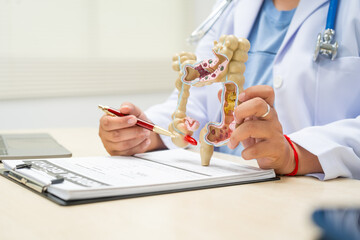 A female doctor sits at a table in a hospital, discussing intestinal health issues, including...
