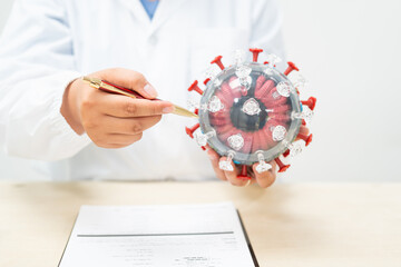 A female doctor sits at a table in a hospital, discussing the COVID-19 virus.She explains the...