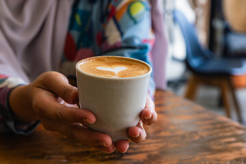 woman holding a cup of latte with latte art in the coffee shop