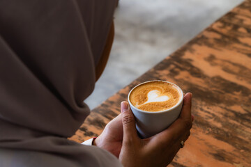 woman holding a cup of latte with latte art in the coffee shop