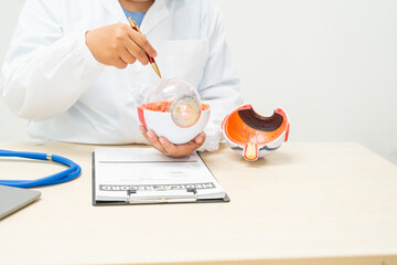 A female doctor at a desk in a hospital, discussing eye diseases such as color blindness,...