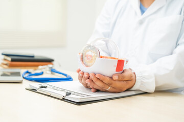 A female doctor at a desk in a hospital, discussing eye diseases such as color blindness,...