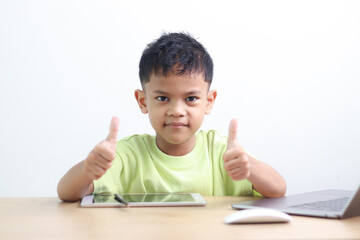 A Happy little asian boy studying online learning class with online video call zoom teacher at home. E-learning or Home schooling education concept.