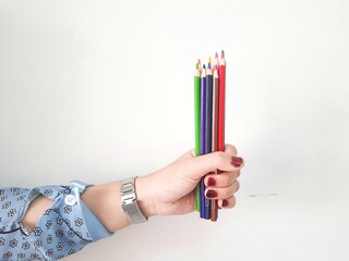 hand holding colored pencils on white background. and paint it on the table using a piece of paper