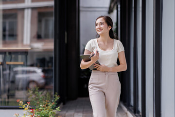 Smiling asian female accountant standing with documents outdoor workplace office
