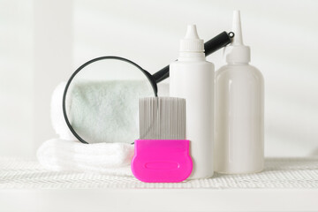 Lice treatment product next to a nit comb and magnifying glass