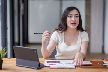 Businesswomen or Asian Accountants using calculator and a tablet laptop computer to analyze business report graphs and finance charts at the workplace, financial and investment concept.
