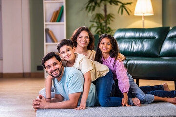 Happy Indian family enjoying quality time at home with father on floor, kids sitting on his back