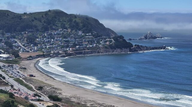 Aerial view of Pacifica State Beach in Pacifica, California, showcasing a beautiful blue sky with a cloud shelf in the background, white sandy beaches, and clear blue water