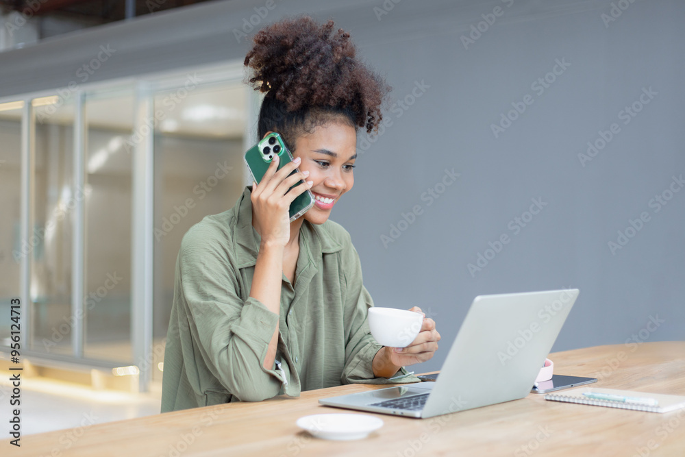 Wall mural african american young woman using smartphone with laptop computer.