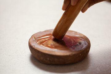 An Indian man is rubbing a sandalwood stick to make sandalwood paste, commonly used in traditional Indian pooja rituals.