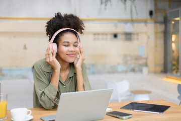 Obraz premium African American young woman using laptop with wear headphones.