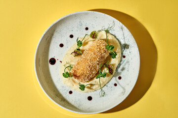 A classic Ukrainian dish, Chicken Kiev, is beautifully presented on a white plate against a vibrant yellow background. The crispy, golden-brown chicken cutlet, stuffed with garlic butter