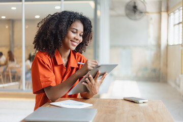 Naklejka premium African American businesswoman excited by the good news on the tablet sitting at office desk.