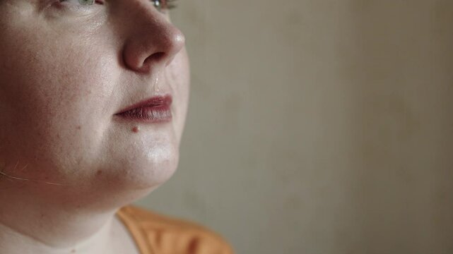 Plus size middle aged woman washes her nose with saline solution at home. Female person sprays sea water into nasal passage and dabs with tissue. Treating runny nose with natural medicine.