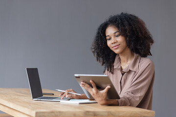 African American businesswoman excited by the good news on the tablet sitting at office desk.